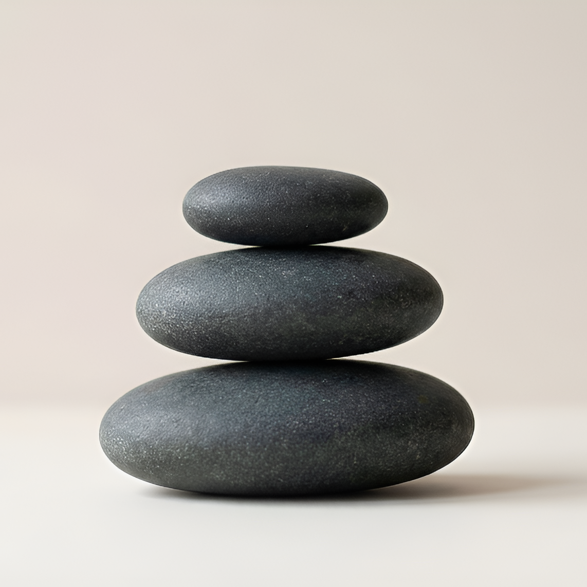 Stack of three balanced stones on a light beige background